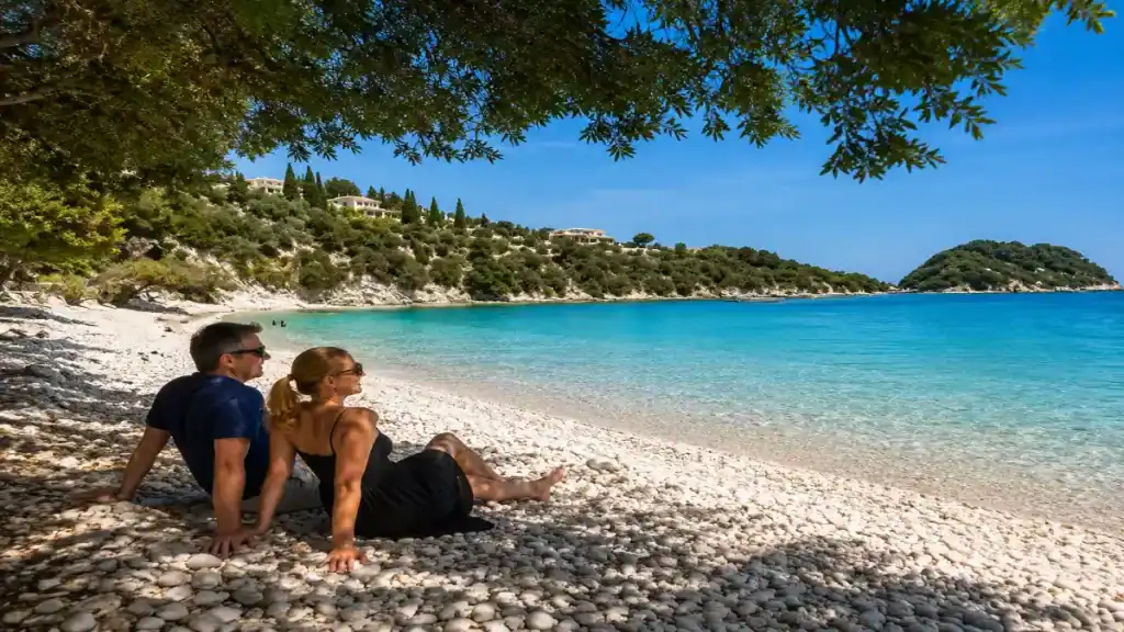 A couple relaxes in shade on the pebbled shore of Levrechio Beach near Lakka.