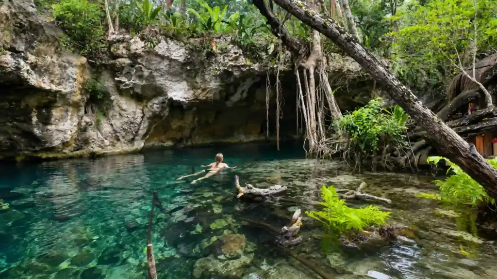 A lone swimmer drifts through Gran Cenote's jungle pool, one reason Tulum is the best base for cenotes.