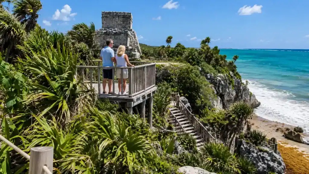 Couple on wooden viewing platform overlooking Caribbean waters near El Castillo temple