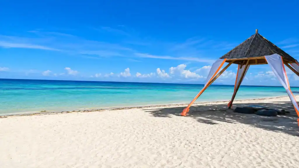 Bamboo beach cabana with orange trim frames turquoise water, showing why Anda can be a day trip escape.