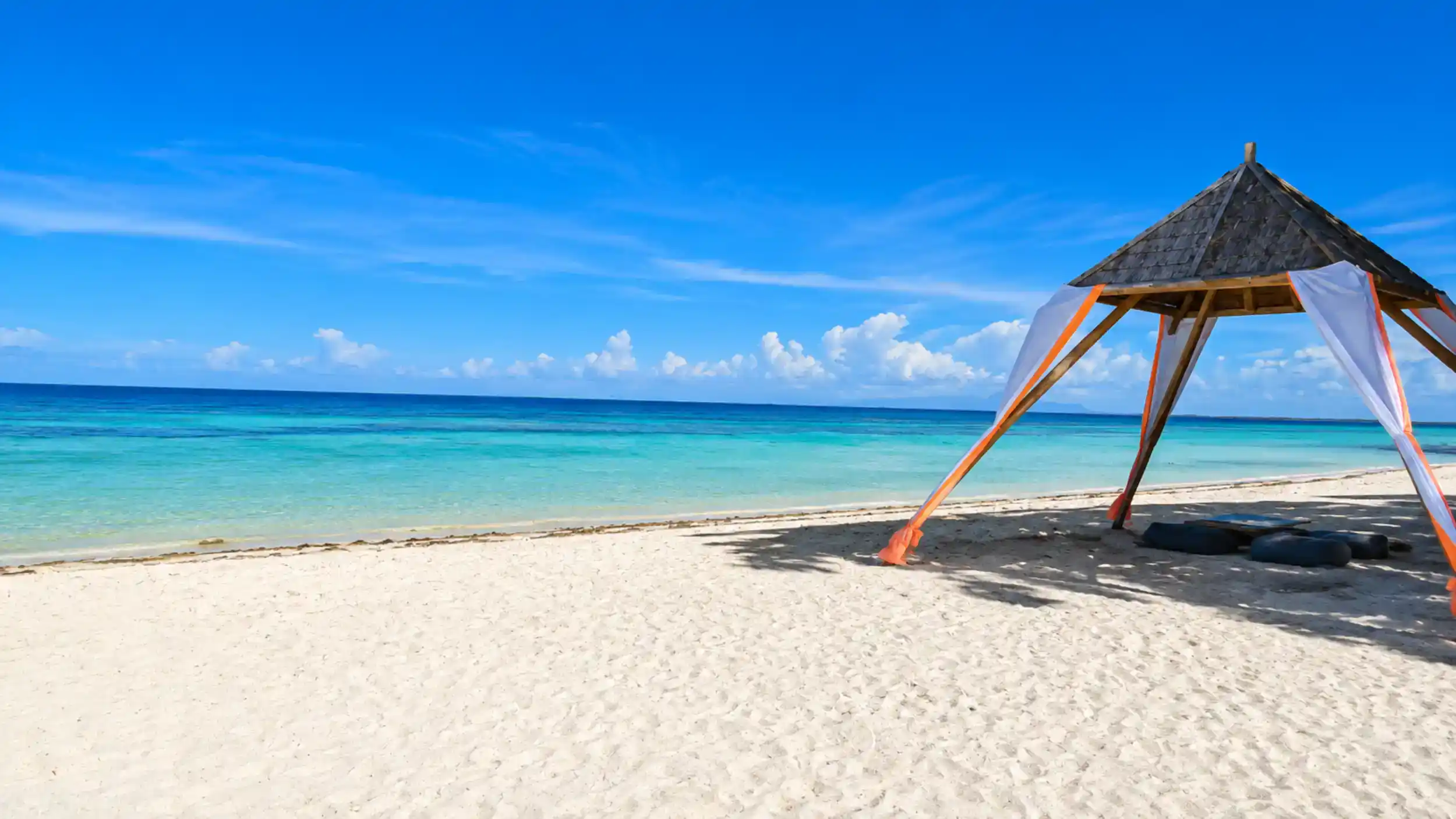 Bamboo beach cabana with orange trim frames turquoise water, showing why Anda can be a day trip escape.