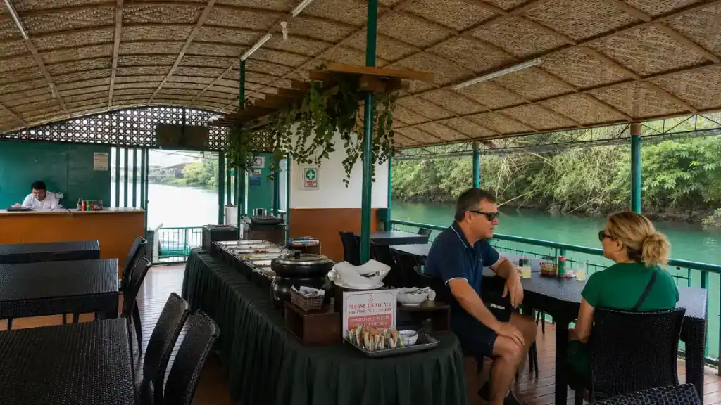 Couple chats over drinks on a shaded floating restaurant along the Loboc River
