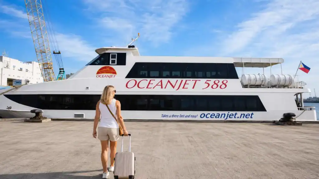 Passenger with rolling suitcase approaching the OceanJet 588 fast craft at the pier