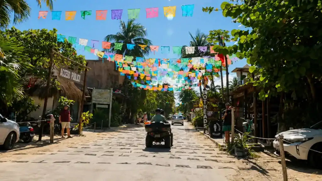 Colorful papel picado banners hang over a sandy street in Tulum, a lively stop when planning how many days in Tulum.