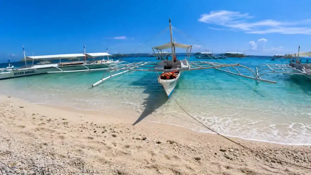 Outrigger boats moored in Balicasag's clear shallows, is Balicasag worth visiting for snorkelling trips.