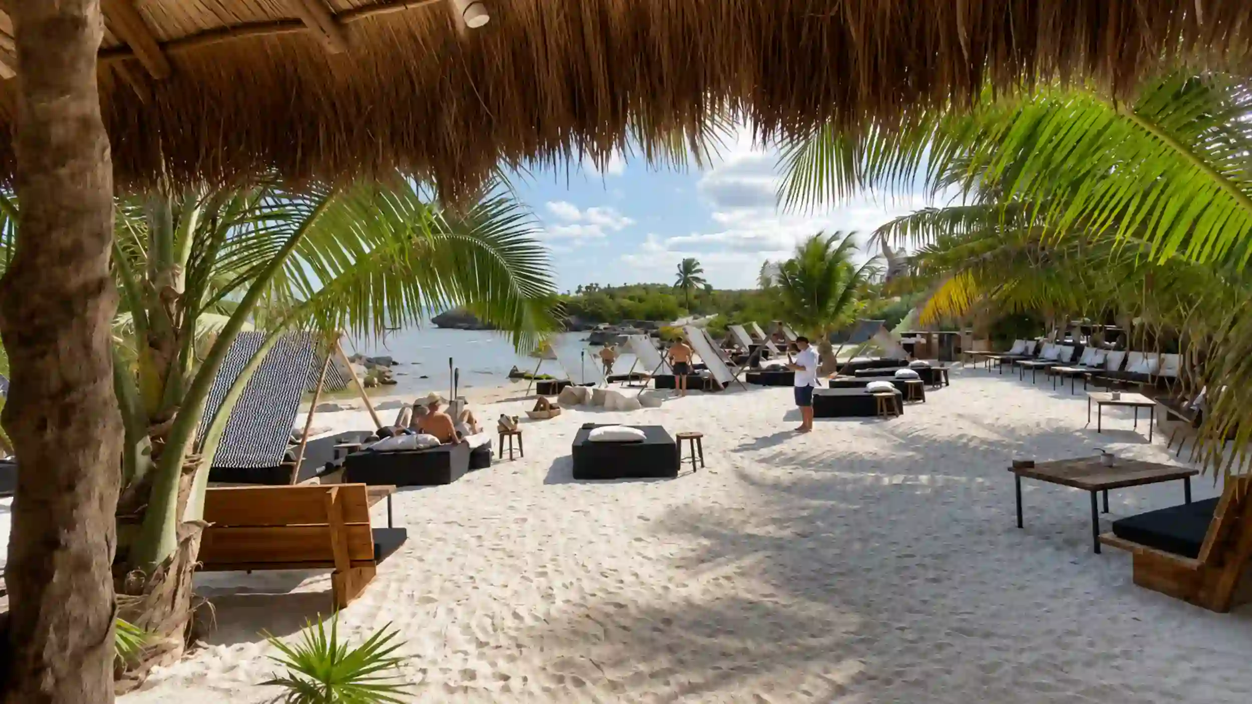 Thatched palapa shades lounge beds at Gitano Beach Club, addressing whether is Tulum too expensive.