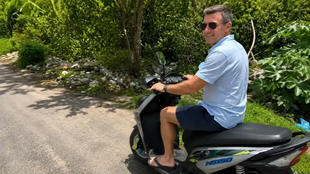 man riding a rented scooter along a jungle road near Tulum, Mexico