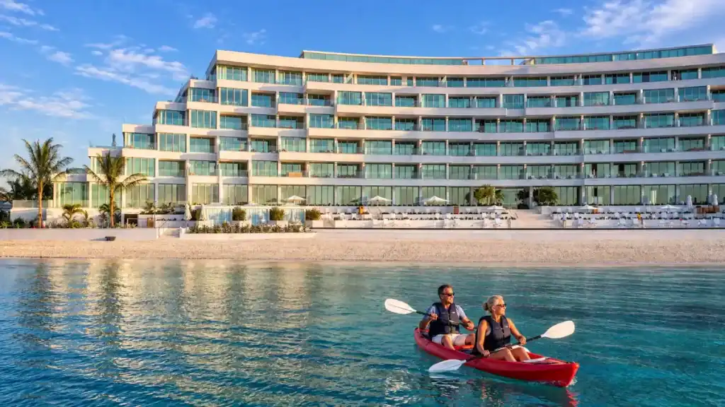 Couple paddles a red kayak past the Rosewood Baha Mar shoreline
