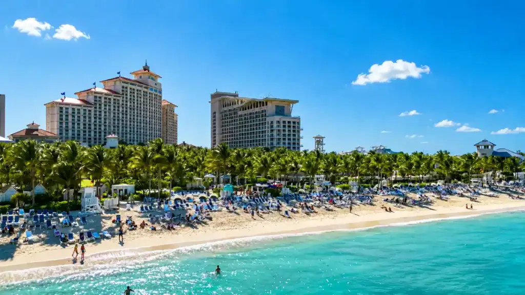 Sunbathers fill lounge chairs along Cable Beach beneath Nassau's resort towers