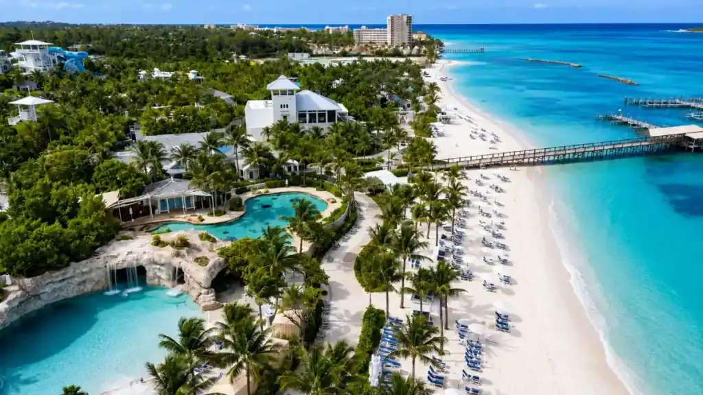 A pier stretches over turquoise water beside Sandals Royal Bahamian's grotto pools on Cable Beach.
