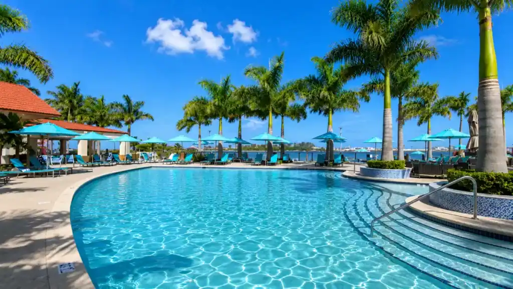 Empty poolside loungers and turquoise umbrellas overlook Nassau Harbour