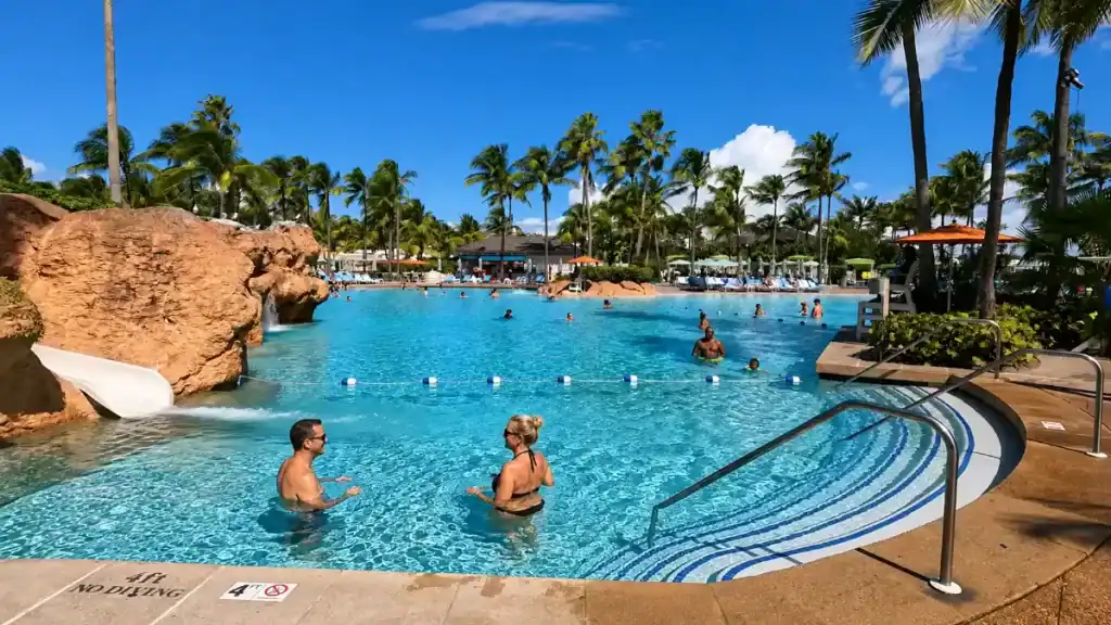 Guests wade in the lagoon pool with rock waterslide at Baha Mar