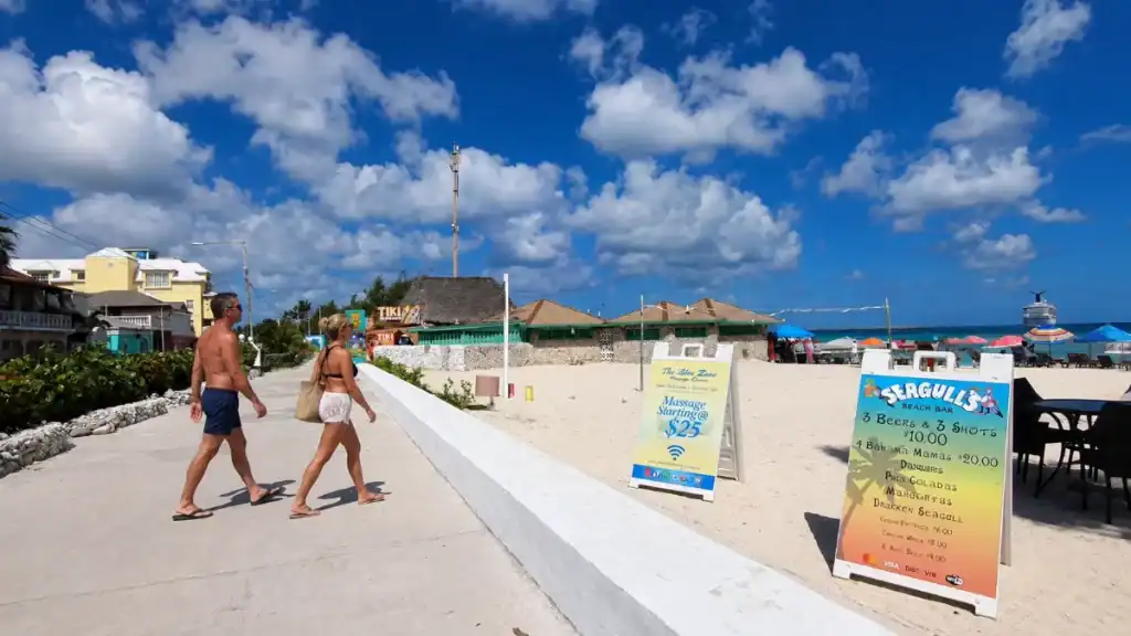Beachgoers stroll a walkway at Junkanoo Beach, a stretch you can reach without needing a car in Nassau.