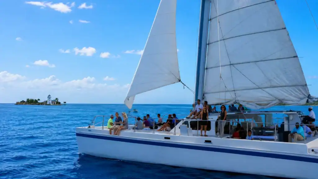 Passengers relax aboard a catamaran sailing past Athol Island lighthouse