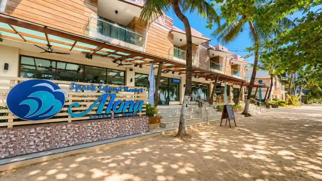 J Park Island Resort's signage and palm-lined entrance sit steps from Alona Beach, a Panglao vs Anda favorite.