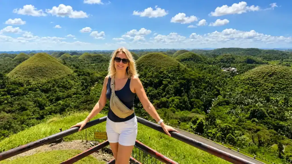 A traveller leans on the railing at the Chocolate Hills viewpoint in Carmen