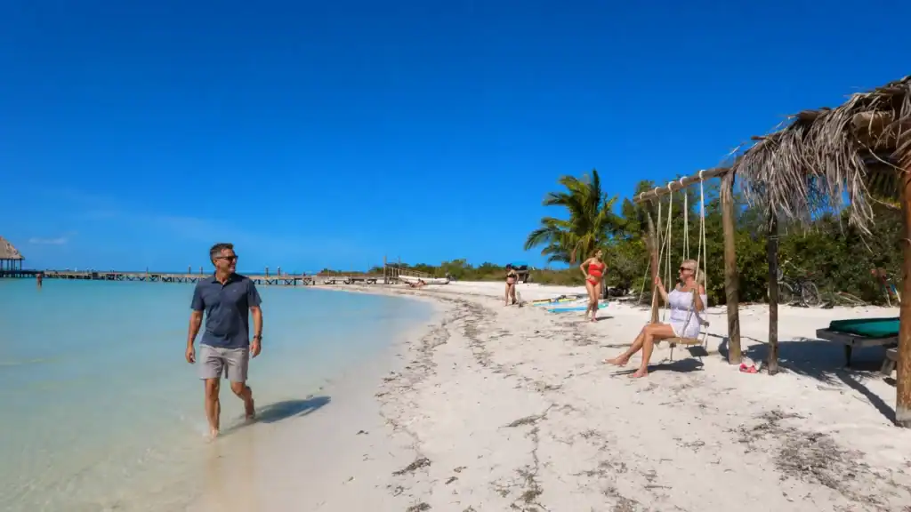 Beachgoers wading and swinging on the shore of Punta Cocos in Holbox