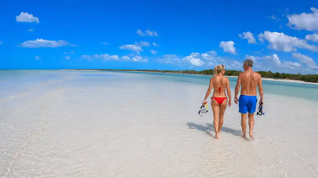 Couple walking the shallow sandbar at Punta Mosquito with snorkel gear, planning how many days in Holbox to spend exploring
