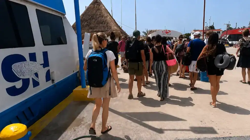 Passengers disembarking past the ferry hull at the Holbox terminal dock
