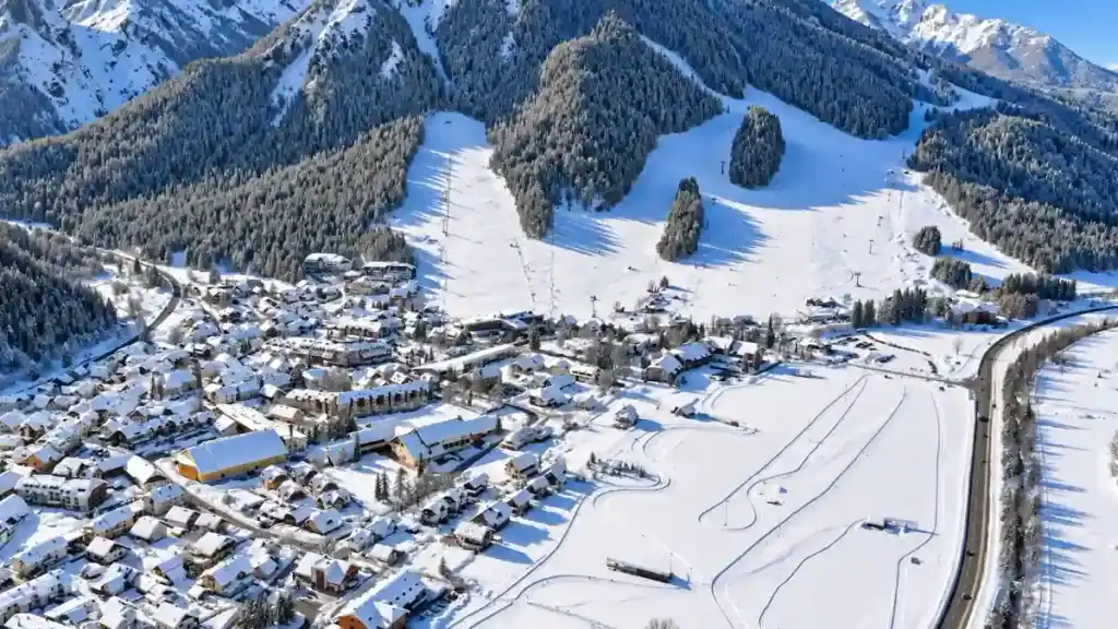 Snow-covered alpine village sits below ski slopes and cross-country trails