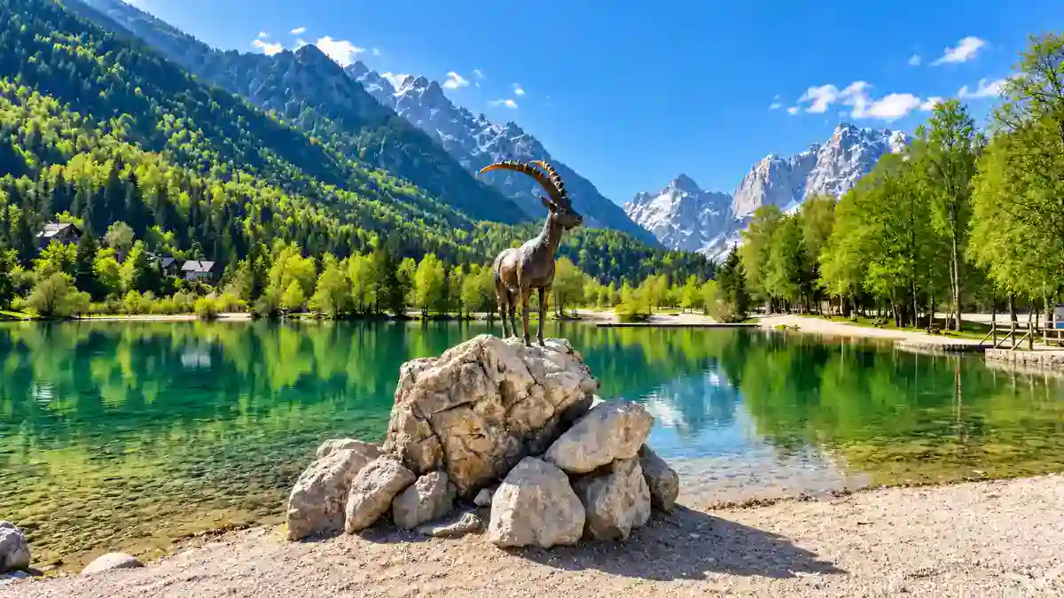The ibex statue overlooks Lake Jasna's turquoise water, illustrating the best time to visit Kranjska Gora in late spring.