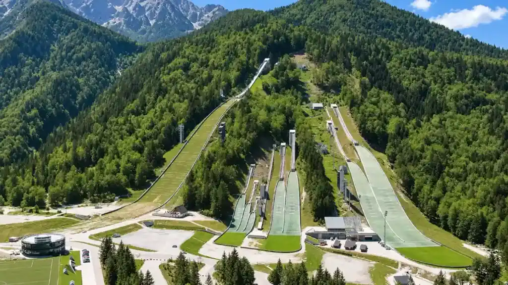 Aerial view of the Planica ski jumping towers cut into a forested valley near Kranjska Gora