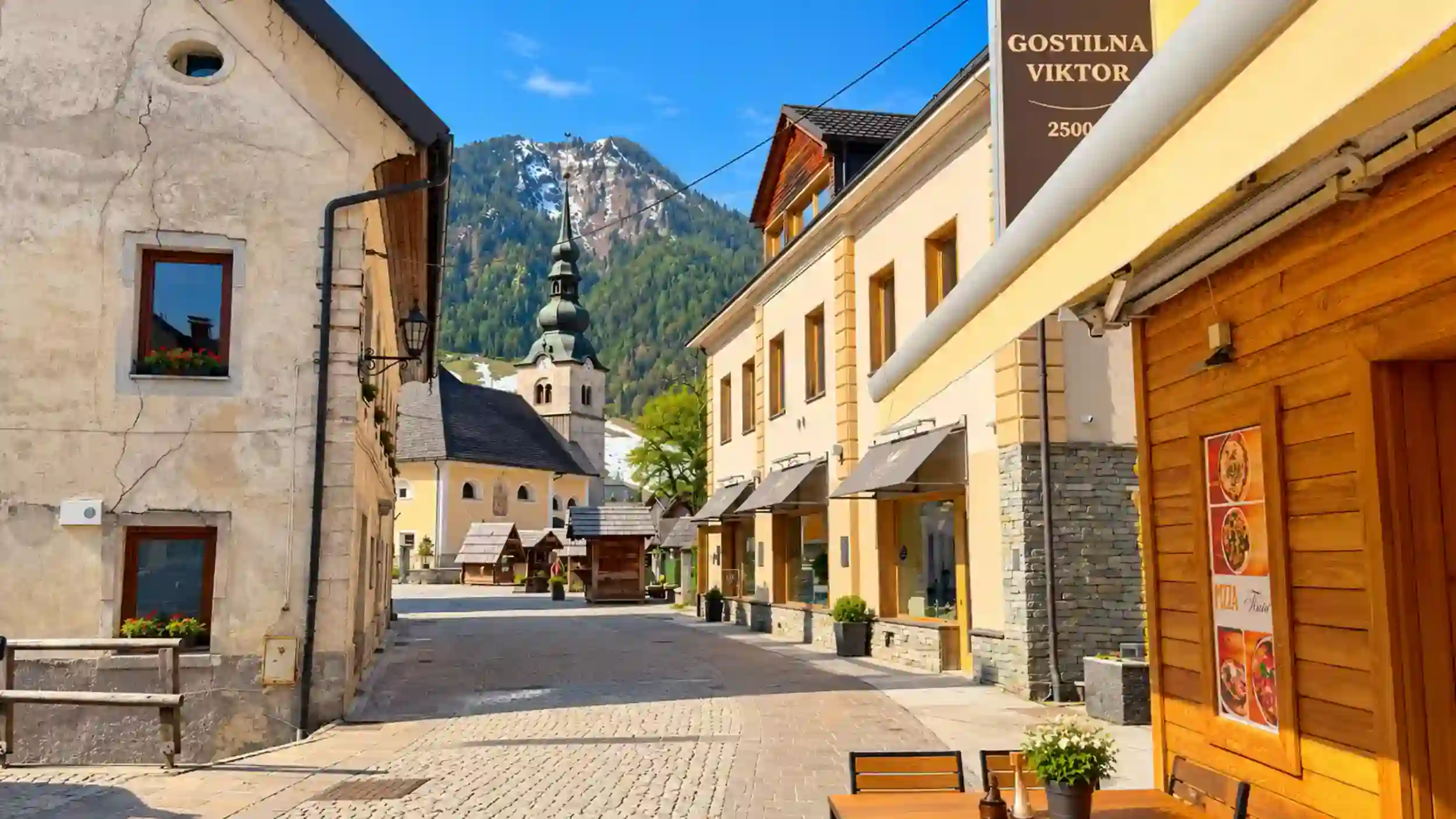 Cobblestone street leads past Gostilna Viktor toward the onion-domed church, a walkable Kranjska Gora scene that answers do you need a car in Kranjska Gora