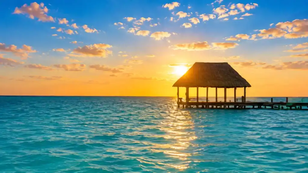 Silhouetted palapa pier glowing at sunset off Holbox's turquoise coast