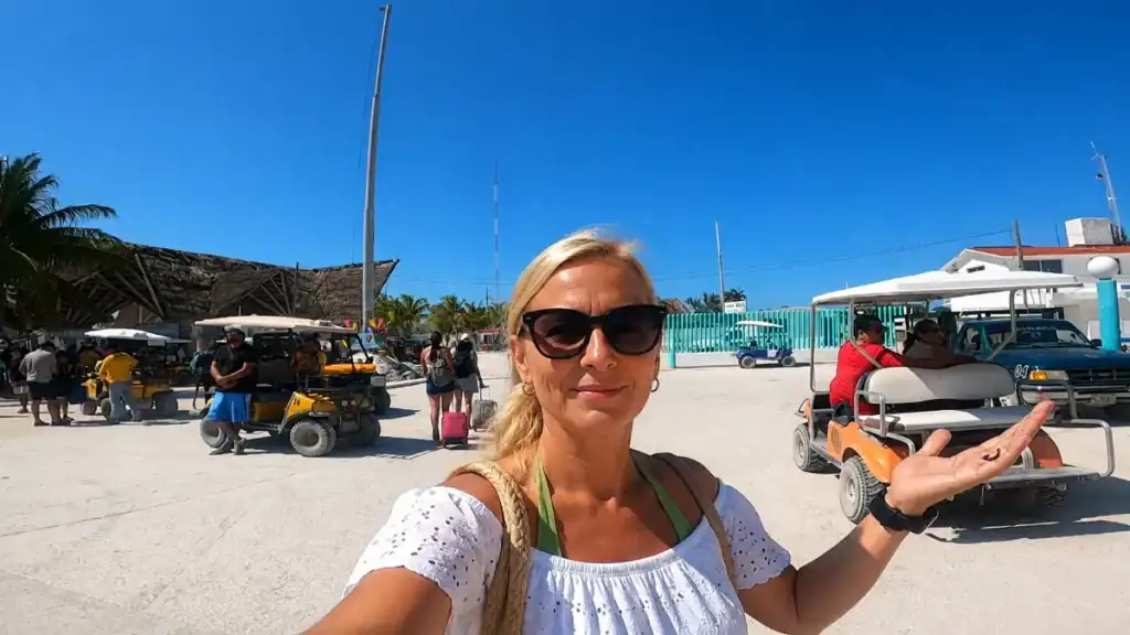 Traveler takes a selfie among golf carts at the Holbox ferry terminal