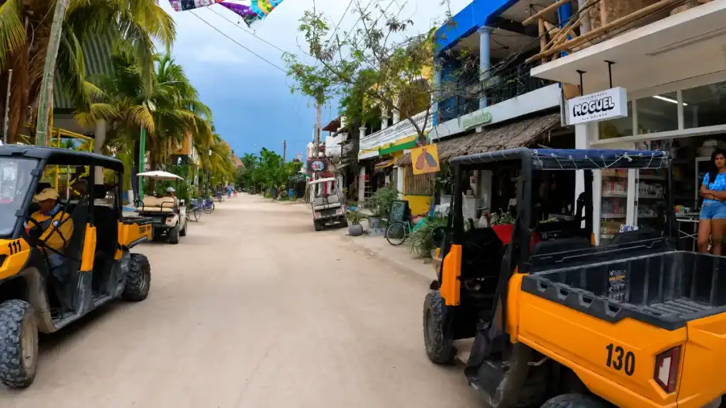 Yellow numbered taxi carts lined up outside shops on a Holbox street