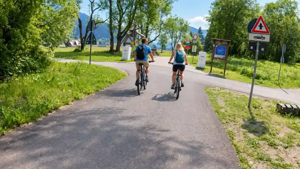 Cyclists pass a border marker on a shared path near Kranjska Gora, one stretch worth building into how many days in Kranjska Gora you plan for cycling