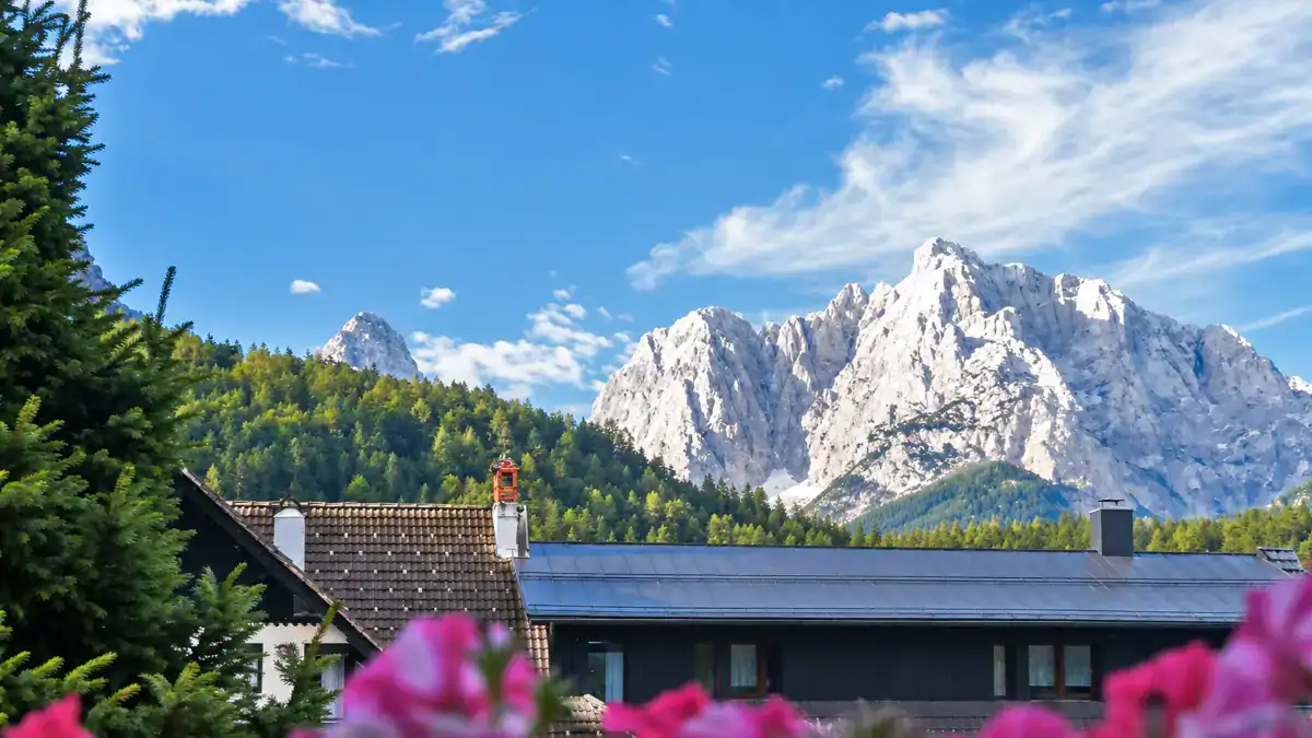 Pink flowers frame chalet rooftops beneath the towering peak of Prisank, a view that alone justifies extra time deciding how many days in Kranjska Gora to stay