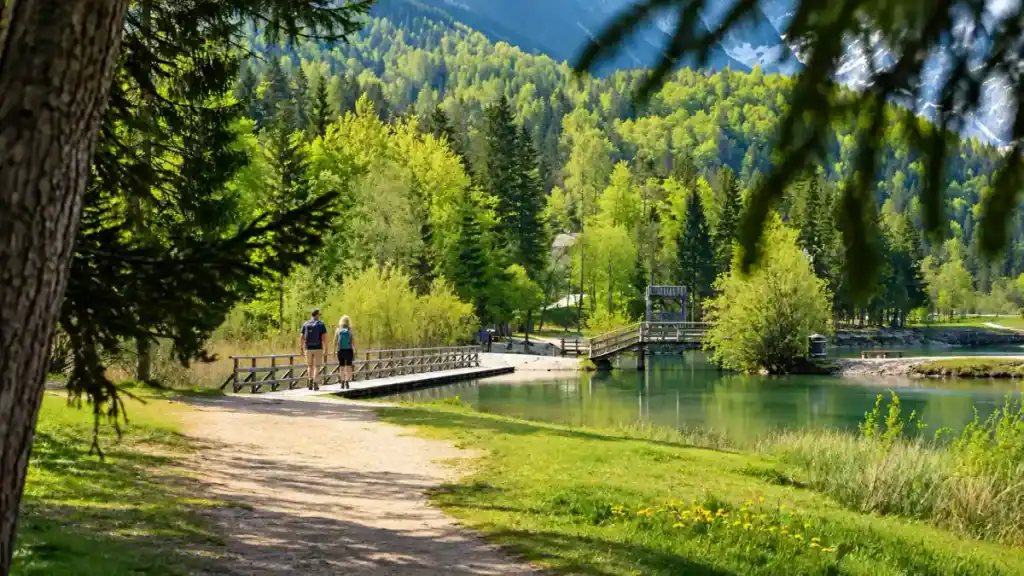 Couple walk a wooden footbridge over Lake Jasna, one of many stops if you're deciding how many days in Kranjska Gora to spend
