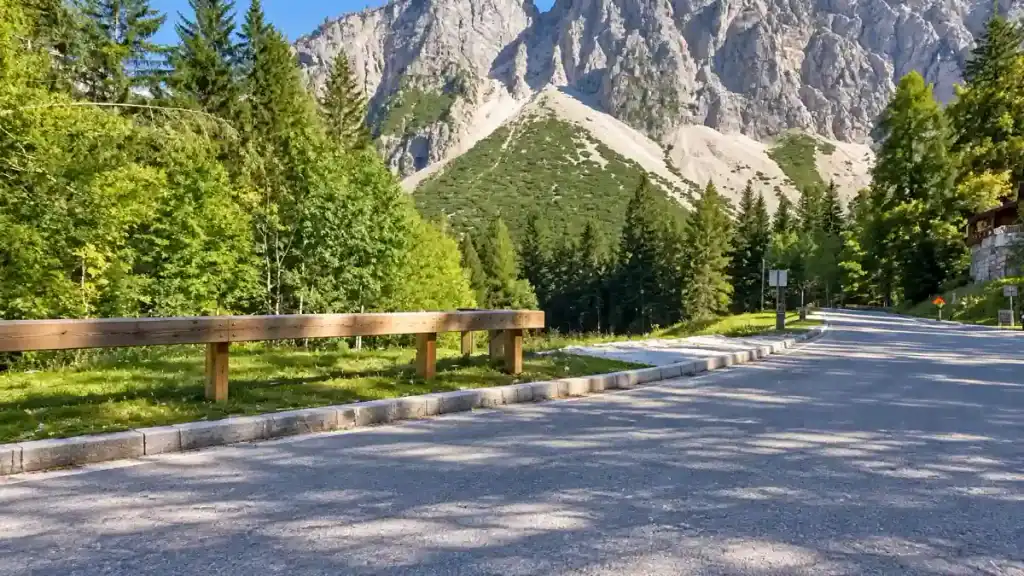 Wooden guardrail lines the road near the base of Vršič Pass beneath scree-covered slopes