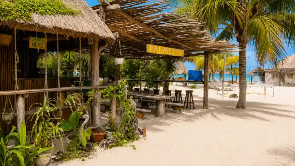Palapa-roofed Palmetto beach bar with wooden picnic tables sits steps from the shore.