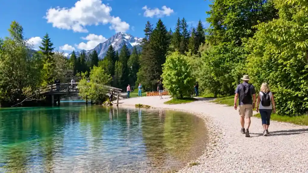 Hikers with backpacks stroll a gravel path circling the Zelenci springs