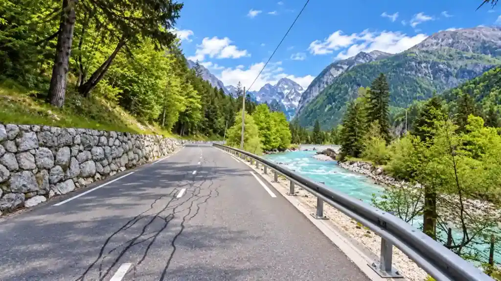 A stone-walled road follows the Pišnica River toward the peaks that make is Vršič Pass worth visiting an easy yes