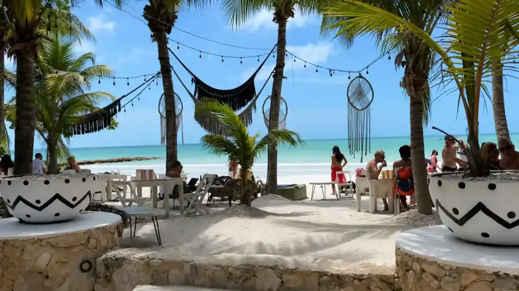 Palm-shaded beach bar with hammocks and dreamcatchers overlooking Holbox or Isla Mujeres shoreline