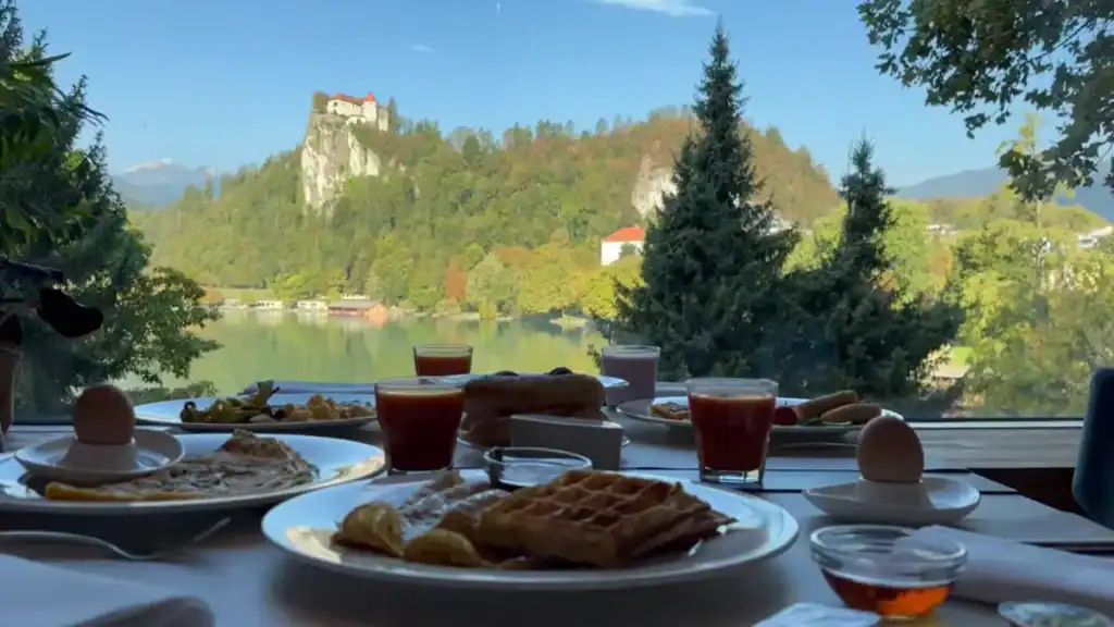 Breakfast table overlooks Bled Castle perched above the lake through a lakeside restaurant window