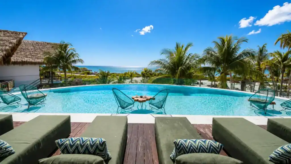 Infinity pool overlooking the ocean at a Holbox hotel with palm trees