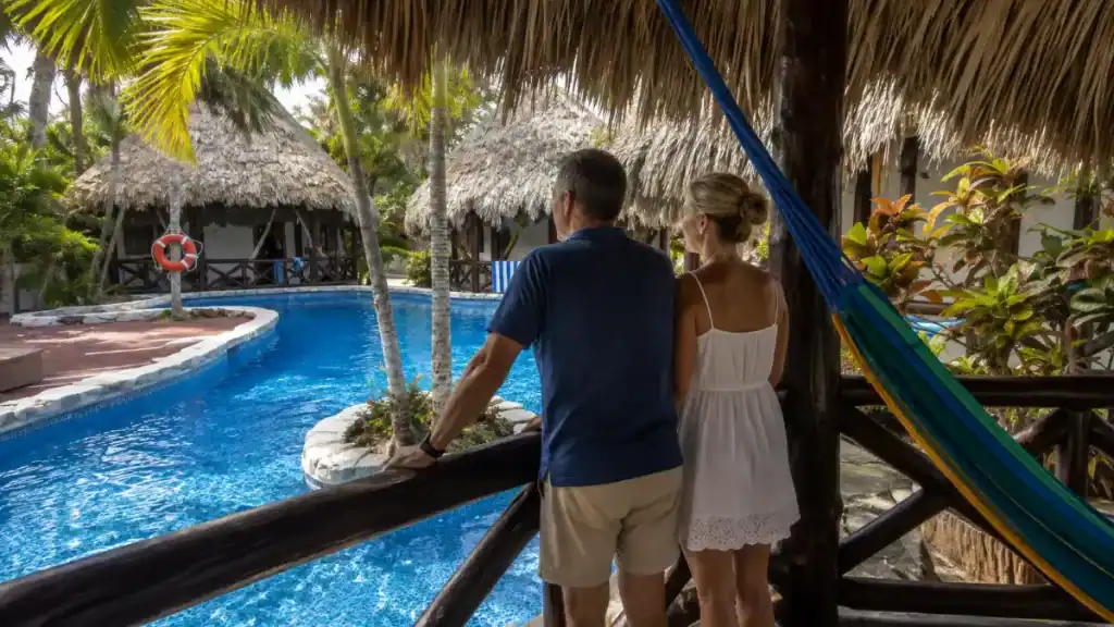 Couple leans on a rail overlooking the palm-ringed pool at Holbox by Xaloc, showing what is Isla Holbox like for resort stays.
