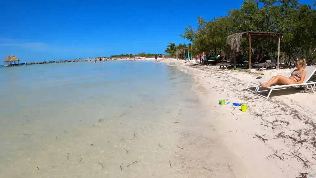Woman relaxes on a lounger beside calm shallow water at Playa Punta Cocos
